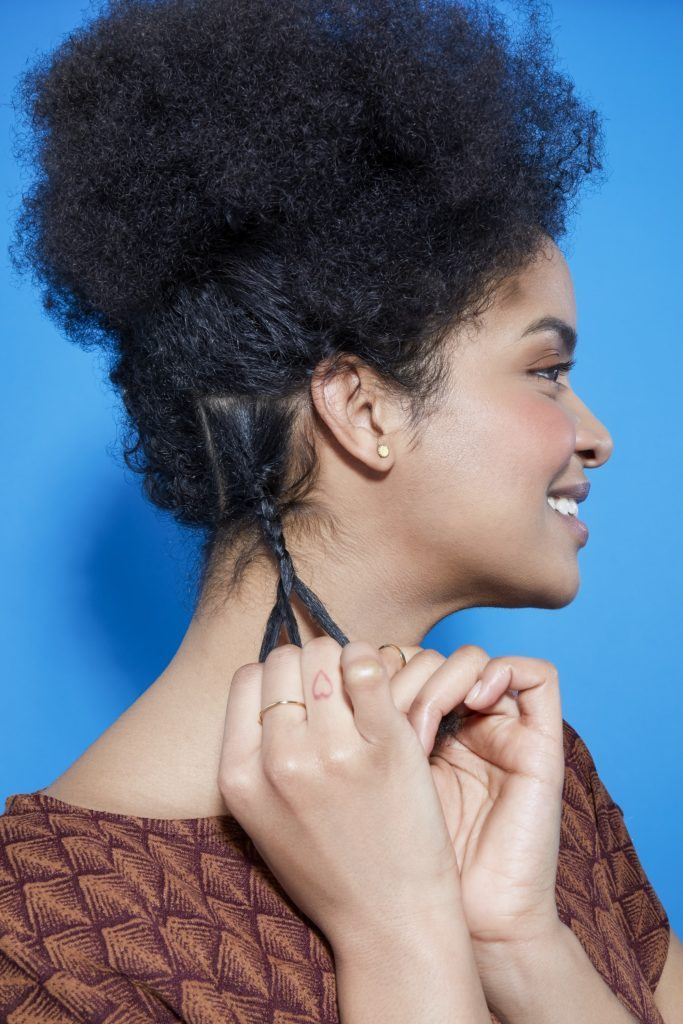 side view of a woman with natural curly hair braiding a small section of hair