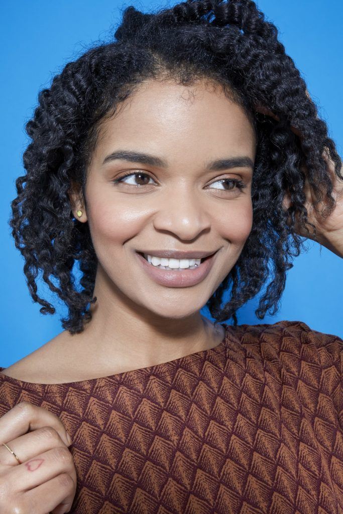 woman with natural curly hair in a bob length cut touching her hair
