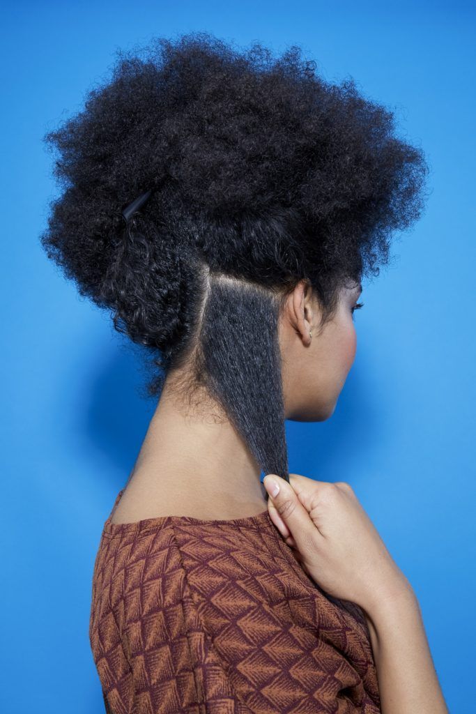 back view of a woman with natural hair separating it into sections ready for braiding