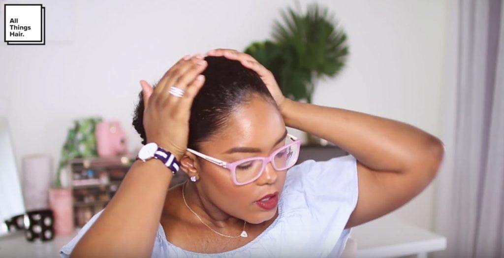 a curly ponytail woman touch her head with her hands