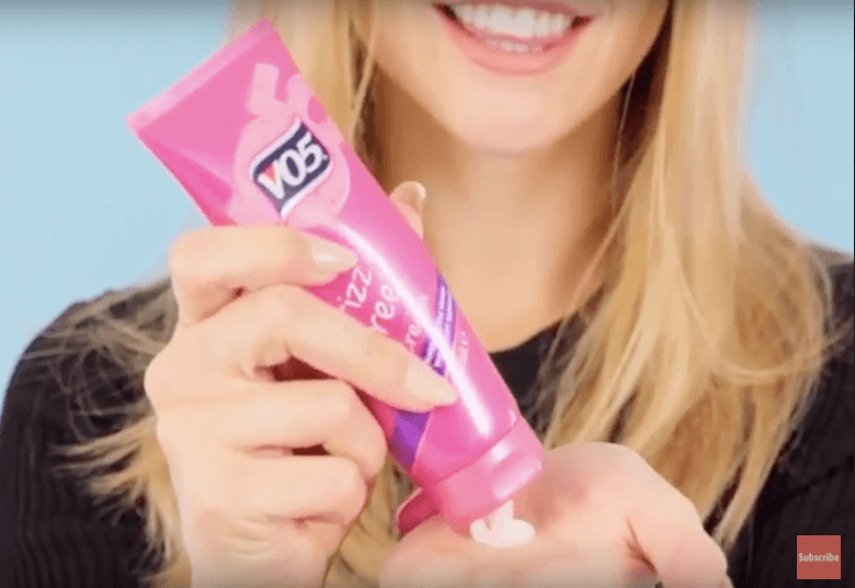blonde model applying product to palm of hand for halo braid tutorial