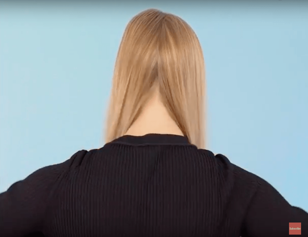 back view of blonde model diving hair into two sections for halo braid tutorial