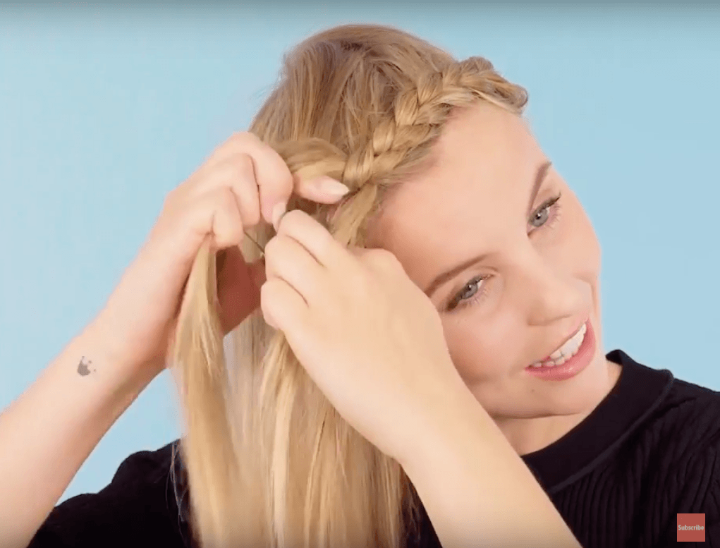 front view of blonde model dutch braiding hair for halo braid tutorial