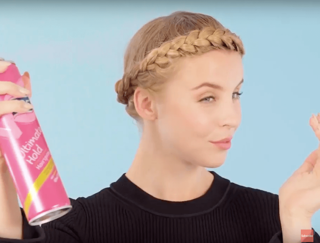 front view of blonde model spraying hair into hair for halo braid tutorial