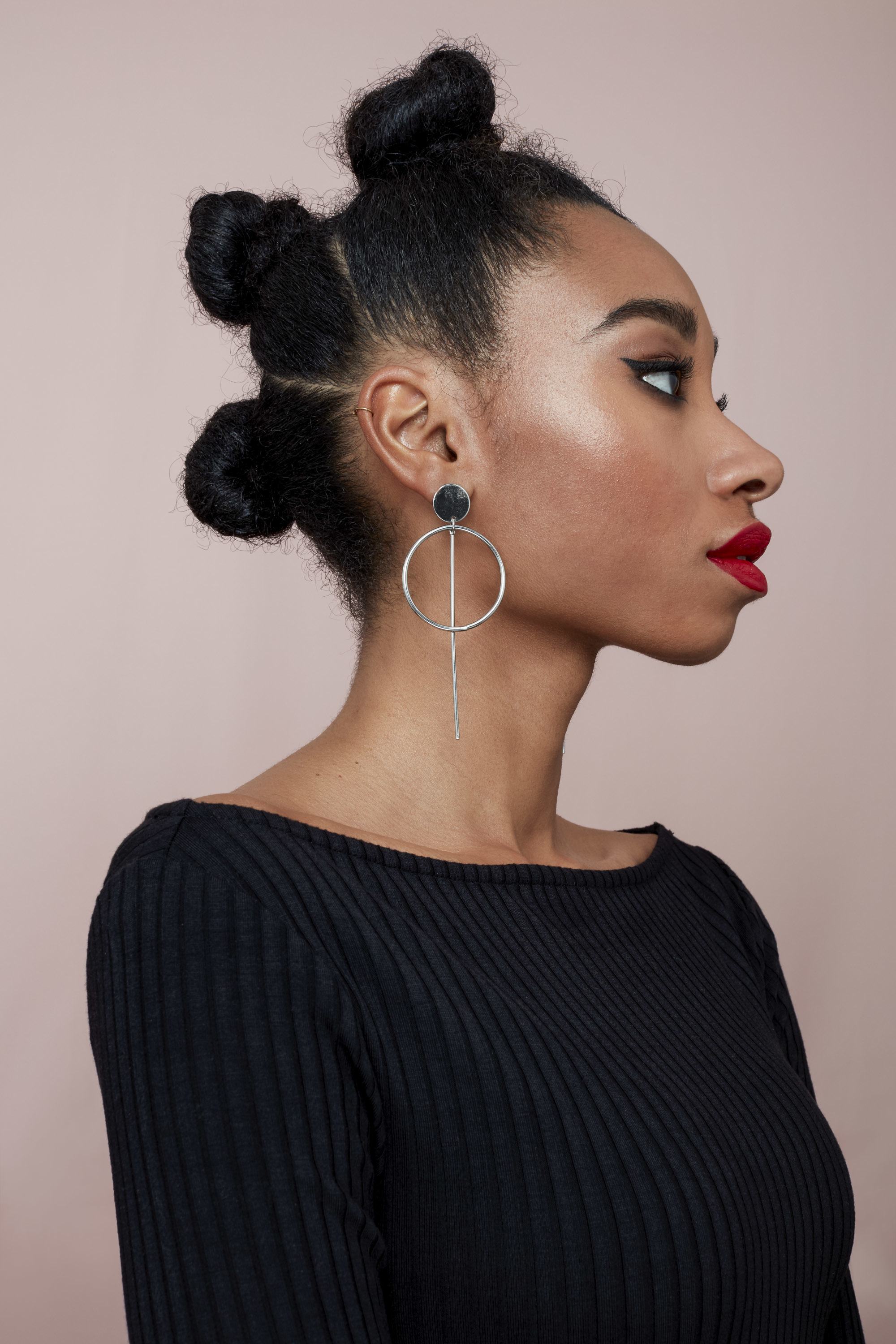 Easy hairstyles for short curly hair: Model with natural curly hair in triple stacked buns wearing a black top and red lipstick.
