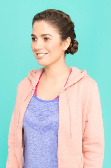 Sporty looking brunette with braided bun wearing a pink hoodie