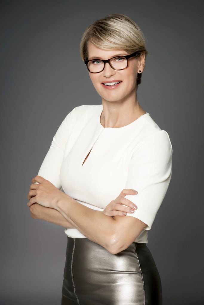 blonde older woman wearing glasses with a sweeping pixie haircut with glasses