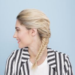 side view of a woman with braided long blonde hair wearing a striped jacket