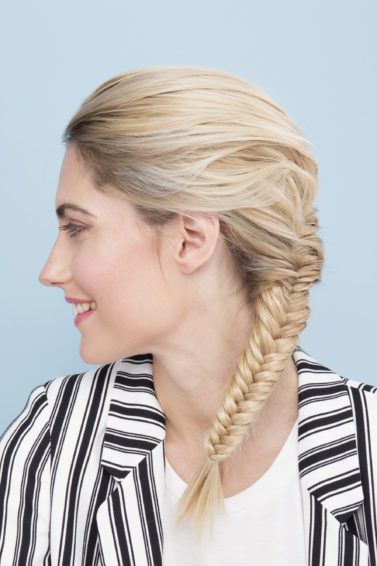 side view of a woman with braided long blonde hair wearing a striped jacket
