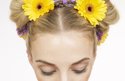 close up shot of blonde model with flowers in her space buns