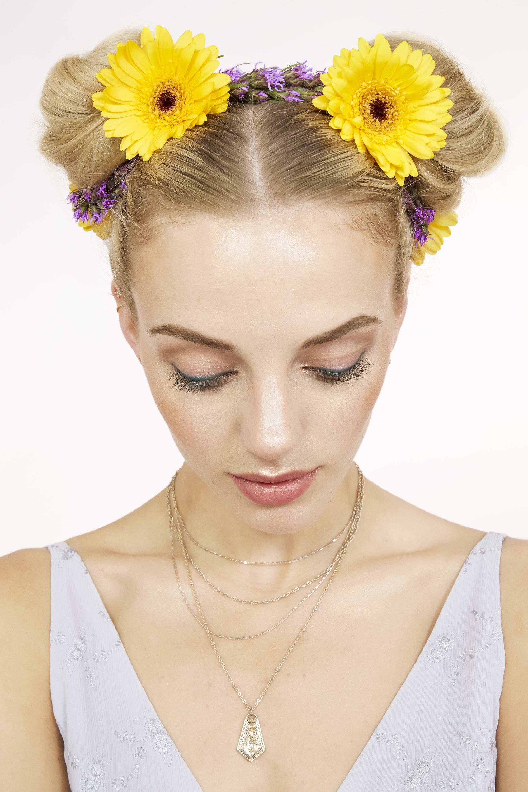 close up shot of blonde model with flowers in her space buns