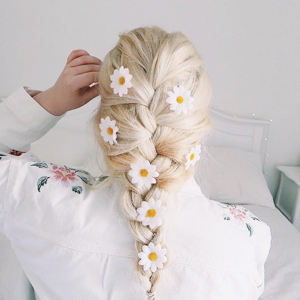 blonde woman with her hair in a french braid with daisy hair accessories
