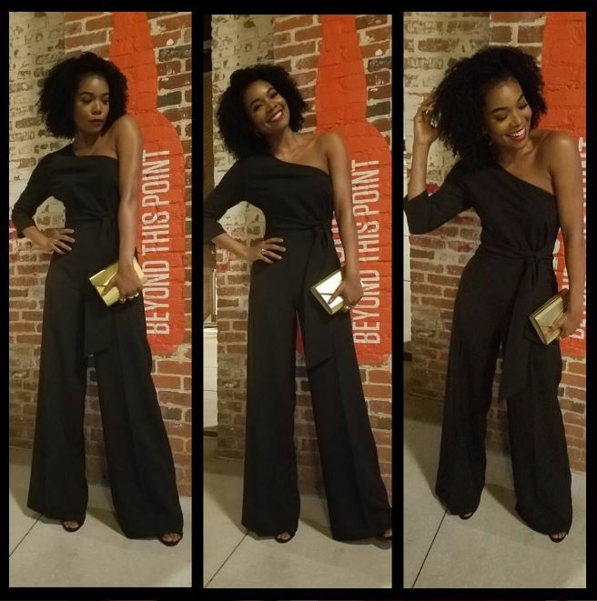 Gabrielle Union with corkscrew curls wearing a one shoulder black jumpsuit