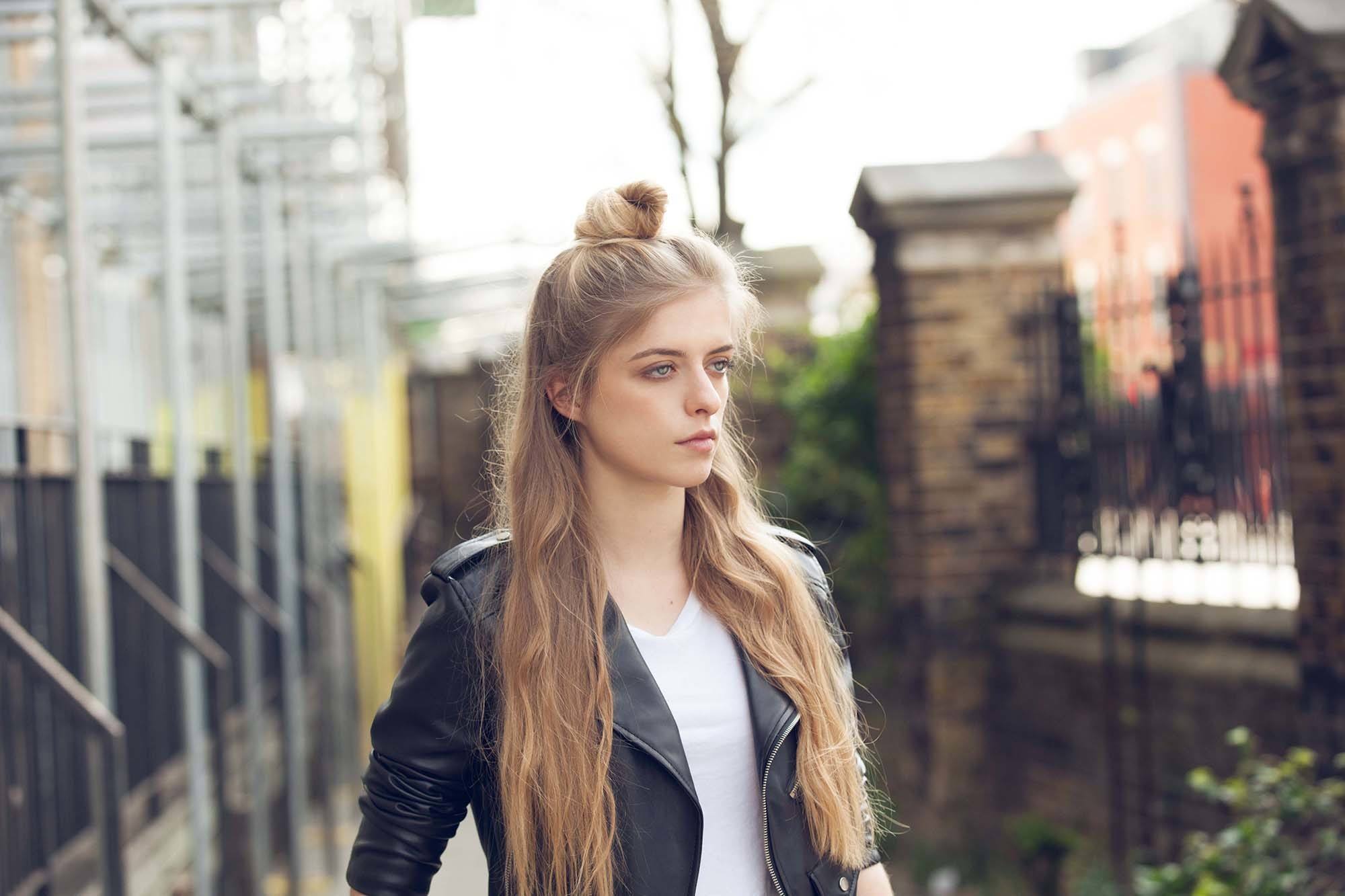 hairstyles for long wavy hair: model with top knot bun half-up, half-down long wavy hair