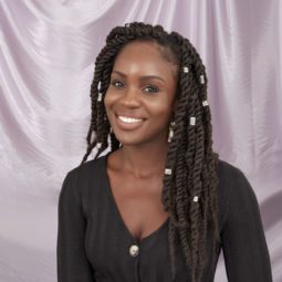 Close up of woman with dark brown marley braid wearing a black button down dress in the in the All Things Hair UK Studio
