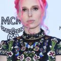 coloured braids: close up shot of mery racauchi with neon pink hair styled into a milkmaid braid, wearing a floral top and posing on the red carpet