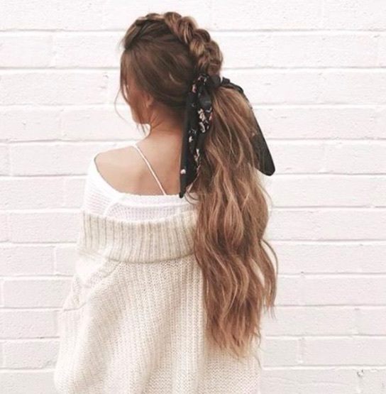 back view of a woman with long brown hair in a mohawk braid style and a low ponytail