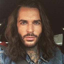 The Only Way Is Essex star Pete Wicks wearing a denim shirt with his long hair worn loose and in waves