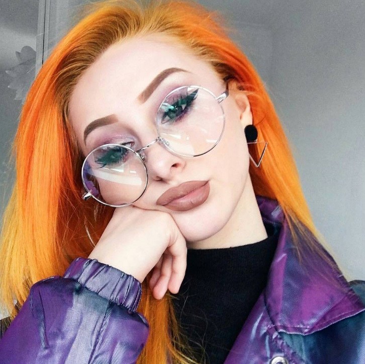 woman with bright orange hair wearing glasses and purple jacket instagram