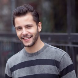 brunette male model wearing a grey and black striped jumper and wearing a quiff hairstyle