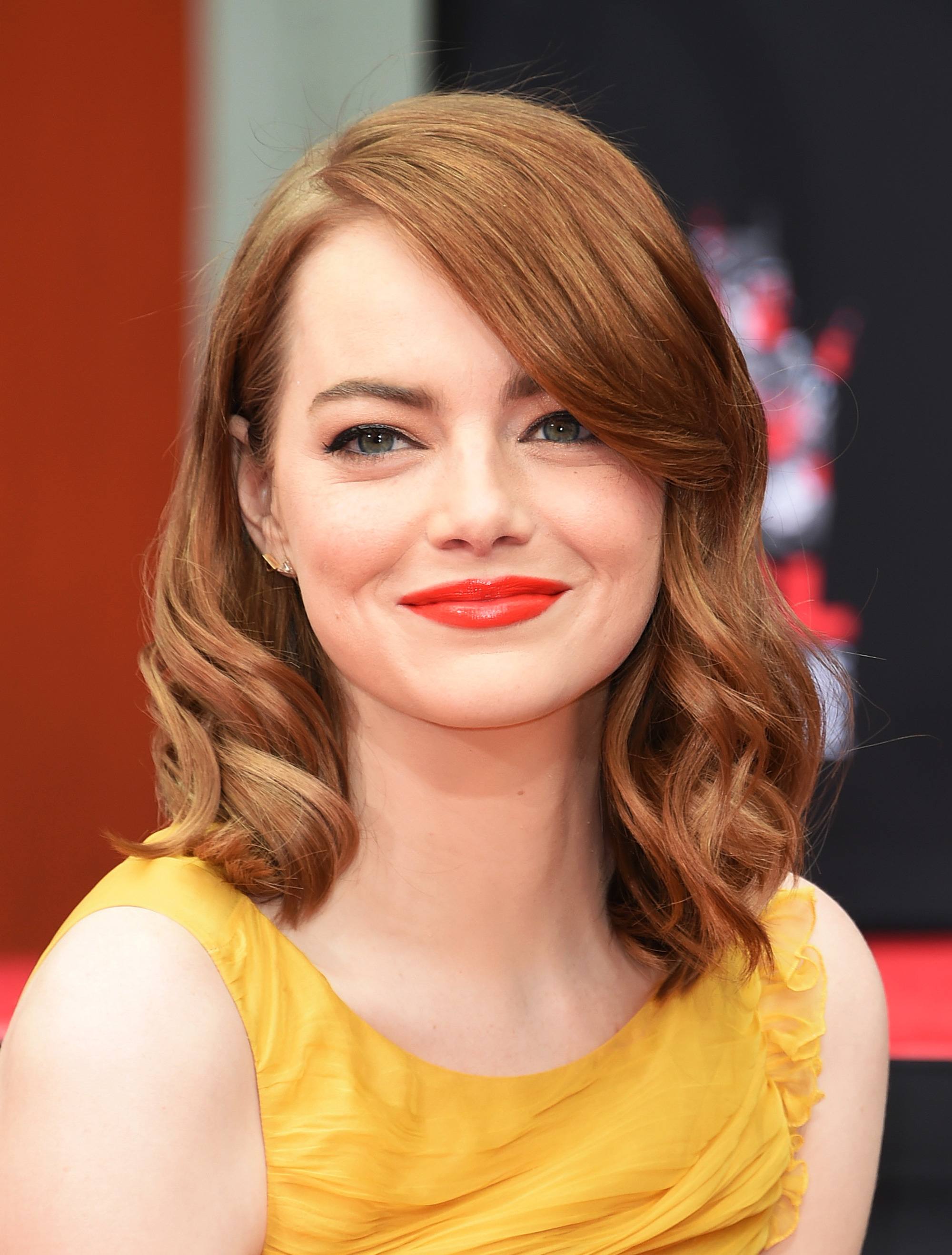 emma stone wearing a yellow dress with her red hair curled