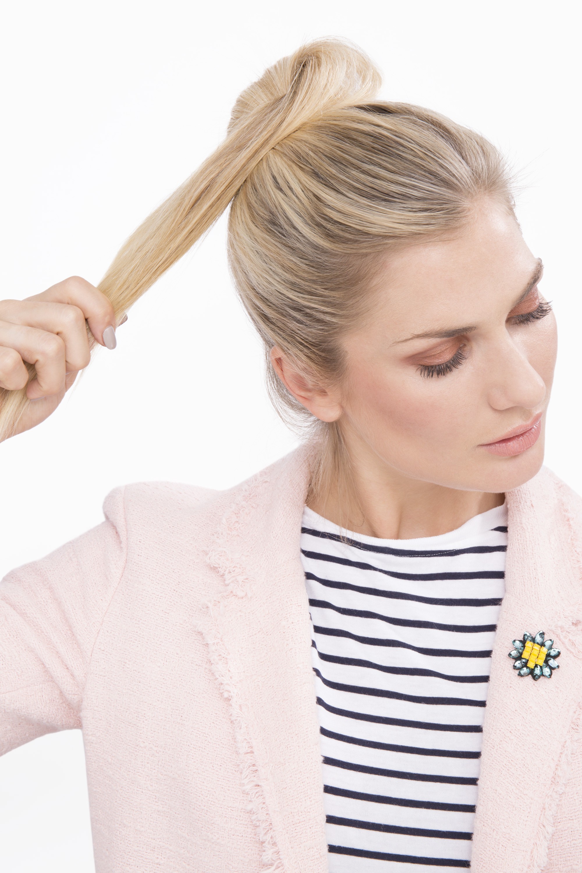 Messy bun: Woman with blonde hair wrapping her ponytail into a bun