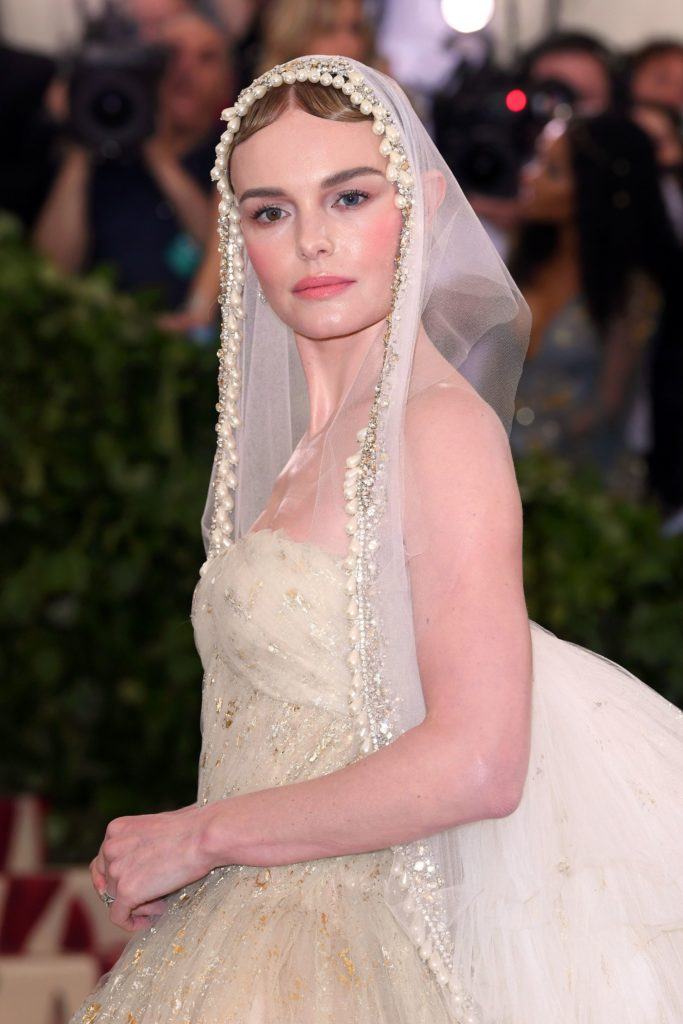 close up shot of kate bosworth with finger waves bun hairstyle and pearl veil hair accessory, wearing all white and posing on the 2018 met gala red carpet