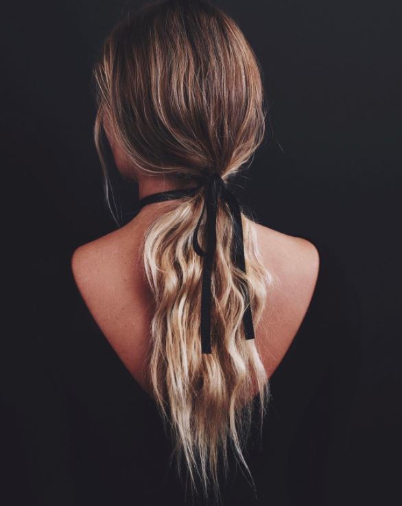 Long blonde wavy hair in low ponytail with ribbon