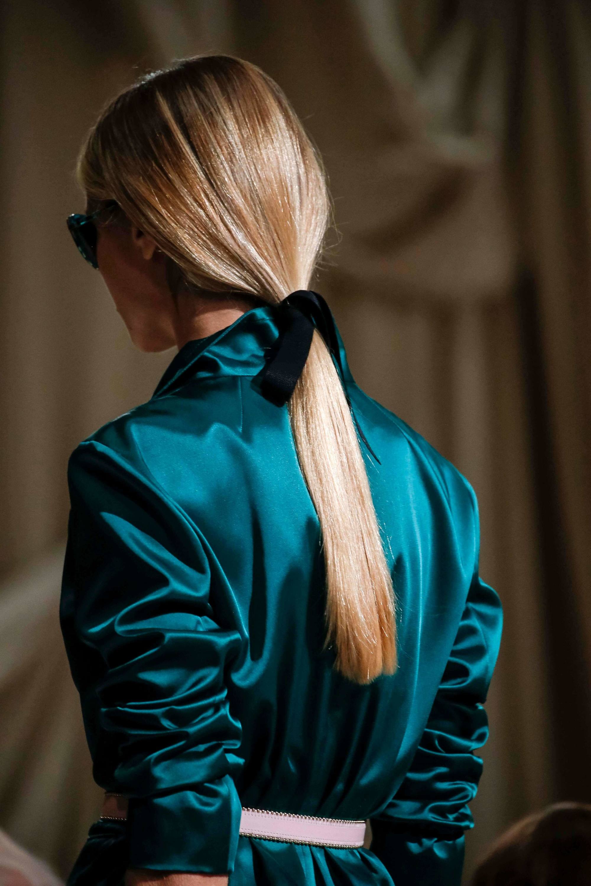 blonde model on the runway with a low ponytail secured with a ribbon - how to get straight hair tutorial