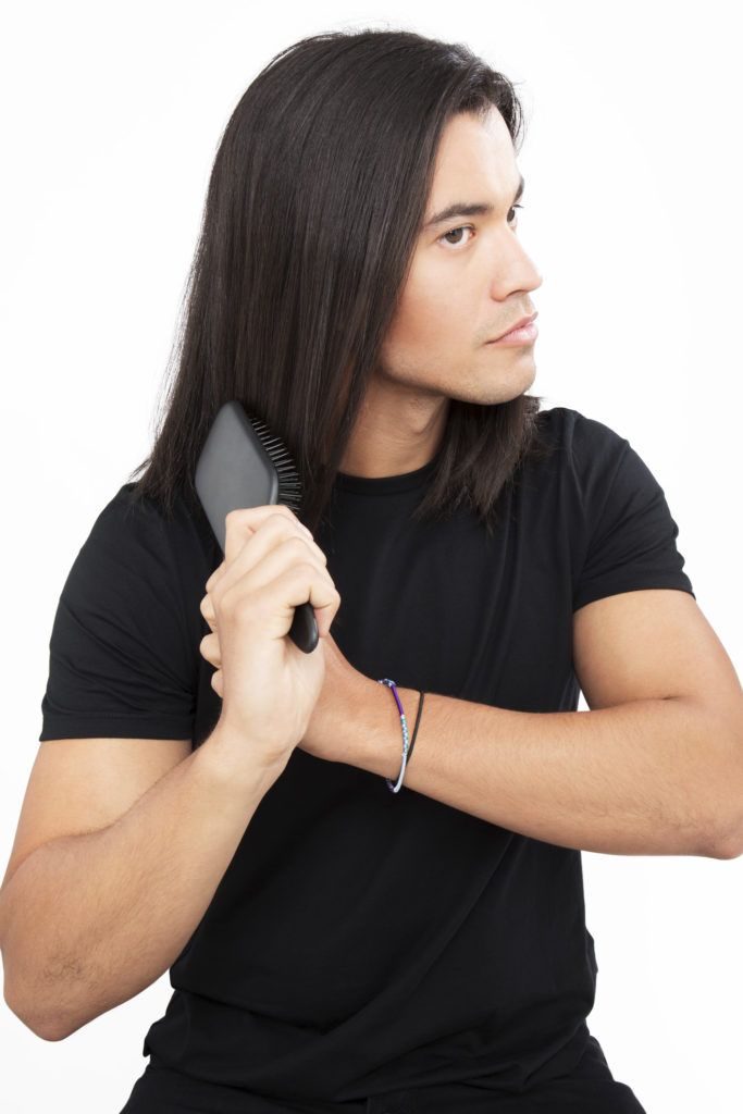 Dark haired man brushing his dark brown hair
