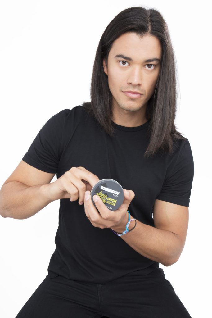 Dark haired man scooping product to his dark brown hair