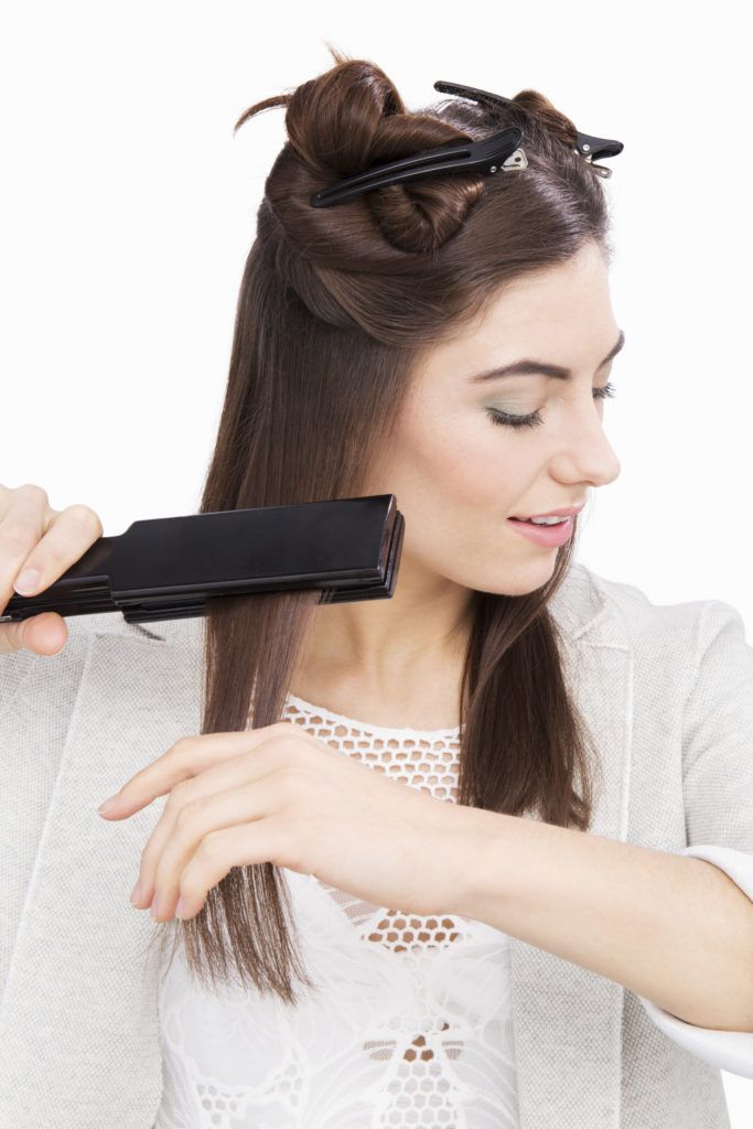 brunette model straightening her hair with a straightener