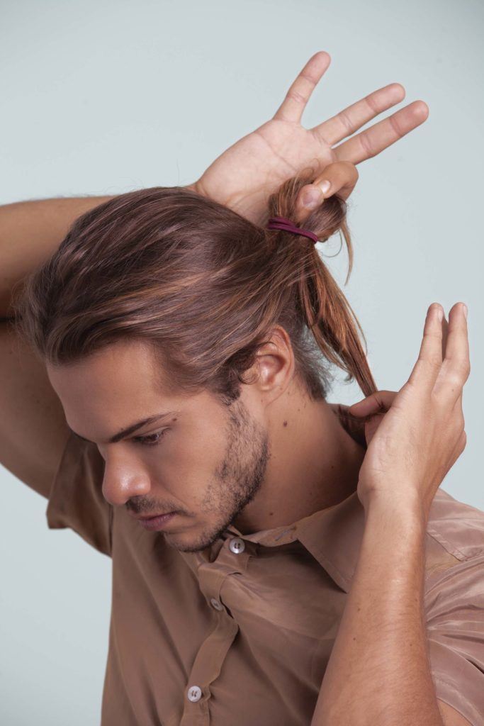 Man bun tutorial man looking away from camera tying hair