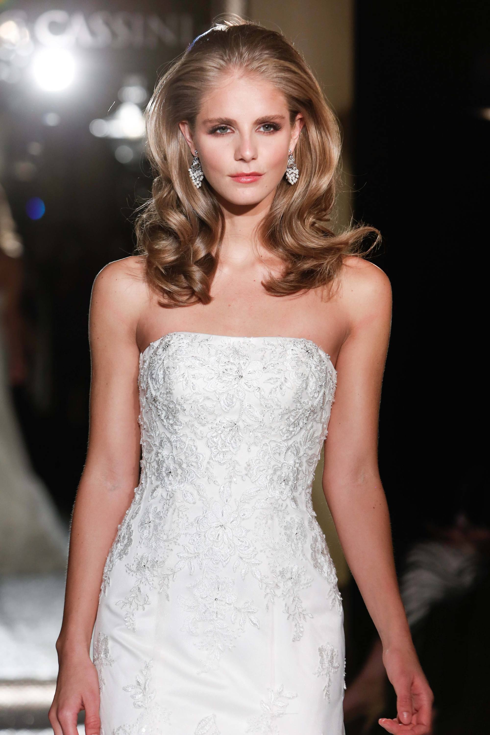 hairstyles for wavy hair: blonde model on runway with large bouncy wavy hair wearing strapless wedding dress