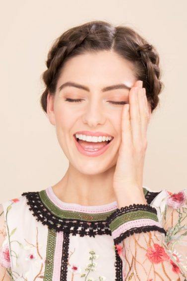 Boots x ATH simple holiday hairstyles: Happy brunette model with halo braid, wearing a floral dress