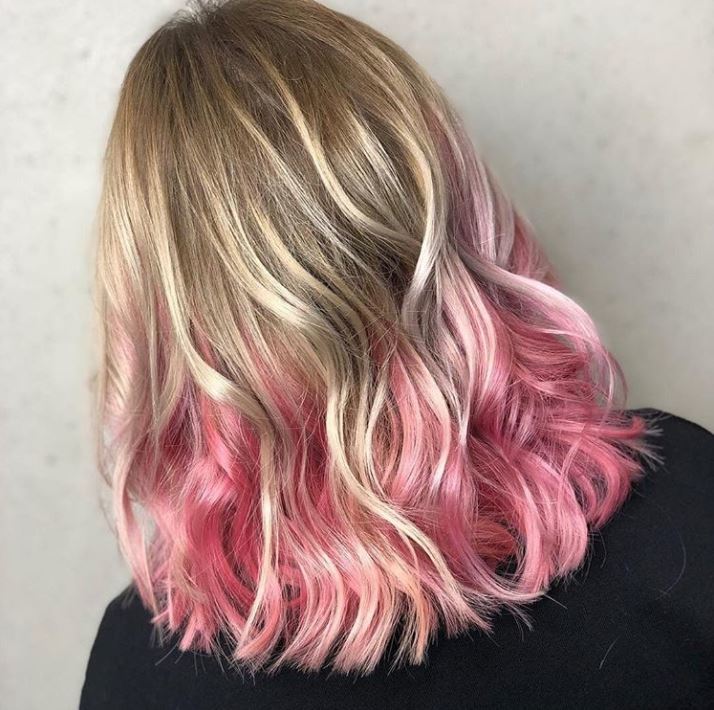 Short ombre hair: Woman with wavy shoulder length blonde hair with pink ombre.
