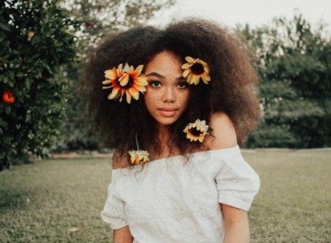 black model with flowers in her afro hair