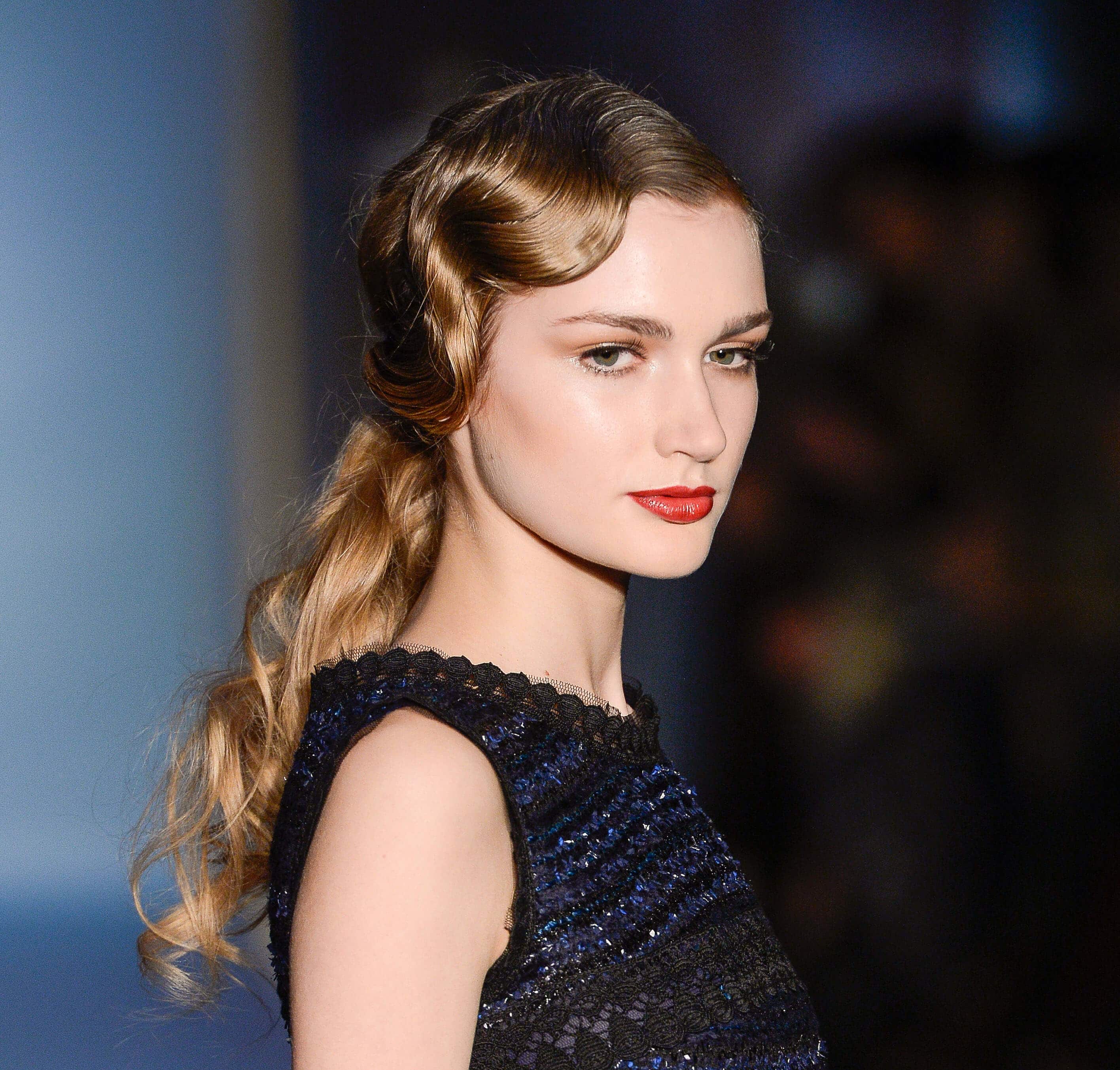 model on runway with golden brown dark blonde long wavy hair styled in a retro finger wave finish