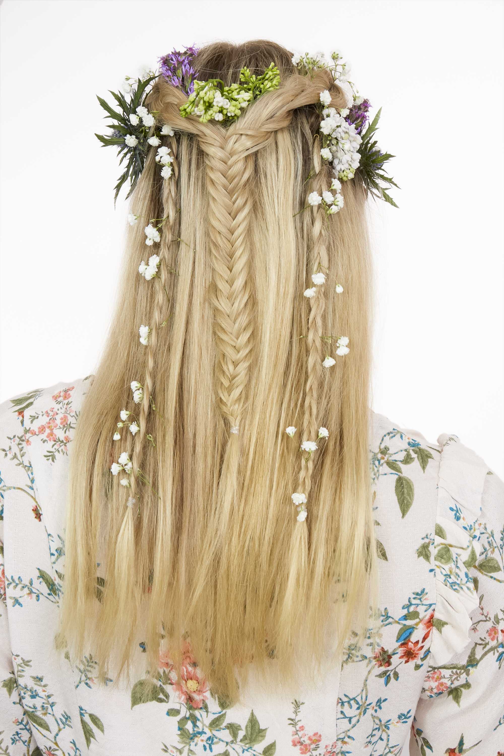Easy Prom Hairstyles: Back shot of a woman with long golden blonde hair styled into a half-up, half-down fishtail braid, complete with flowers.