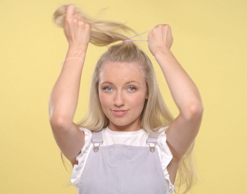 a blonde cute woman tying up her hair