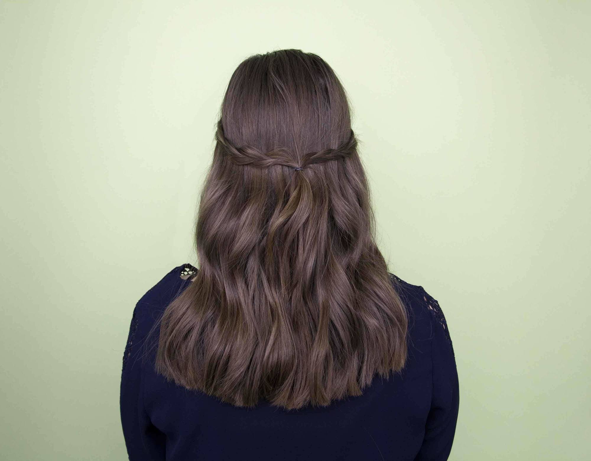 Festival hair: back view of brunette woman with medium length hair styled with single braids pinned at the back in studio setting