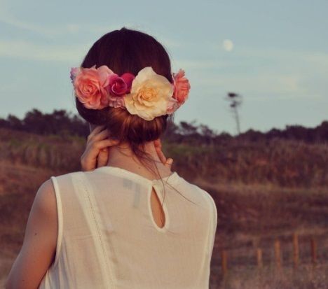 brunette woman with her hair in a rolled gibson tuck updo with flowers