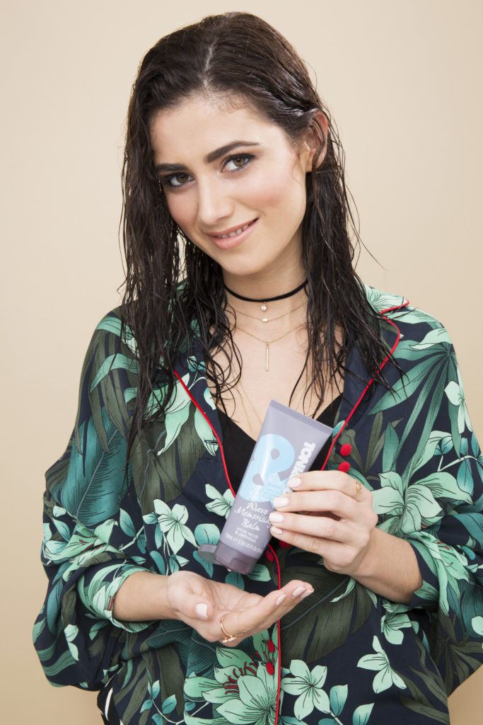 Pin curls tutorial: Dark haired model with damp hair squeezing the T&G Wave Memorising balm into her hand