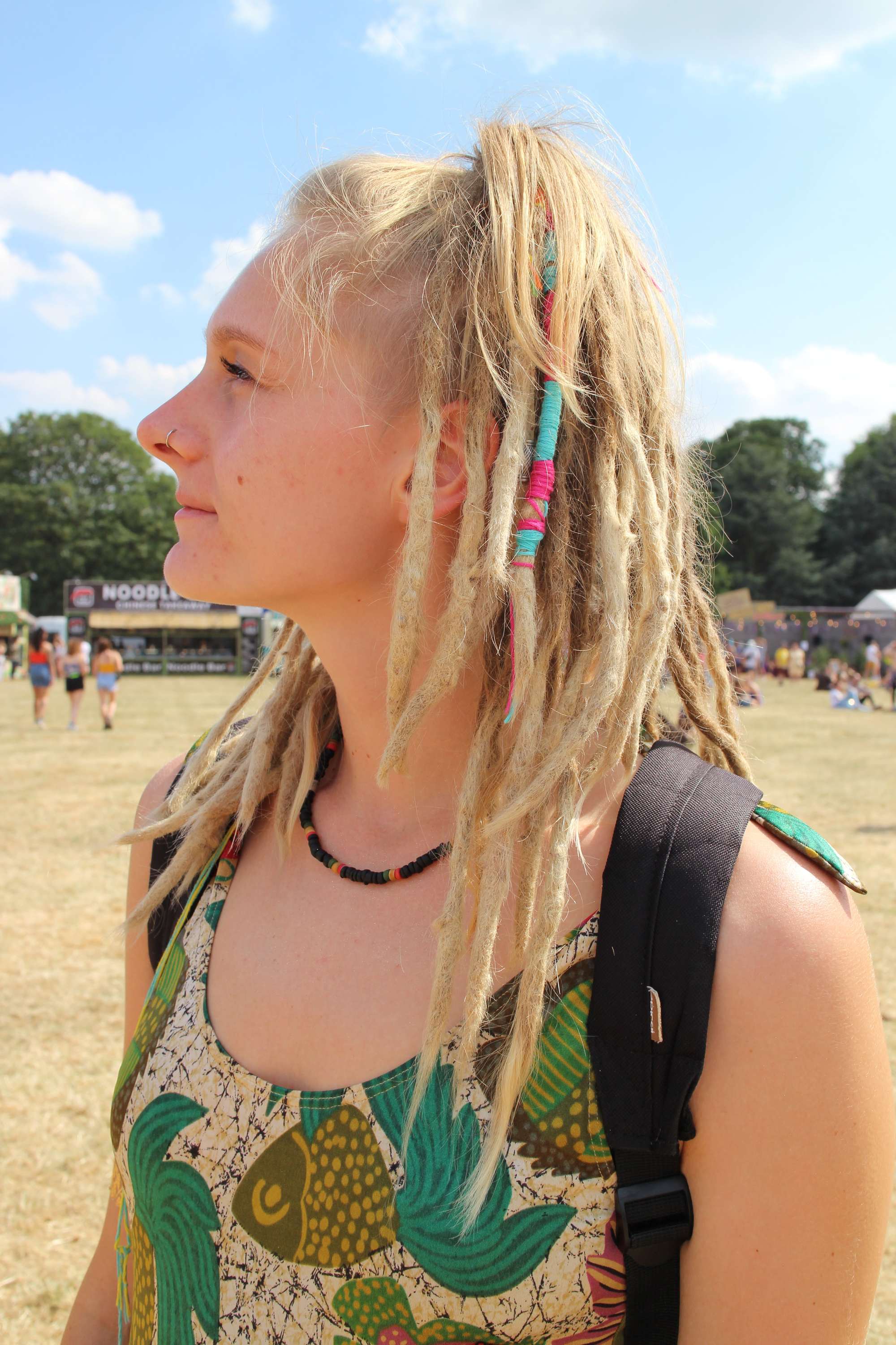 Festival hair accessories: Side view of blonde woman with hair in high ponytail with some strands covered with a blue hair wrap
