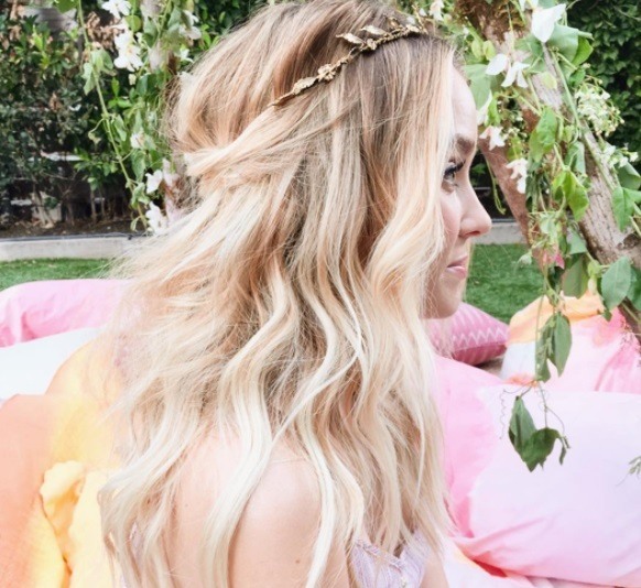Woman with blonde wavy hair in a half-up half-down with a leaf headband