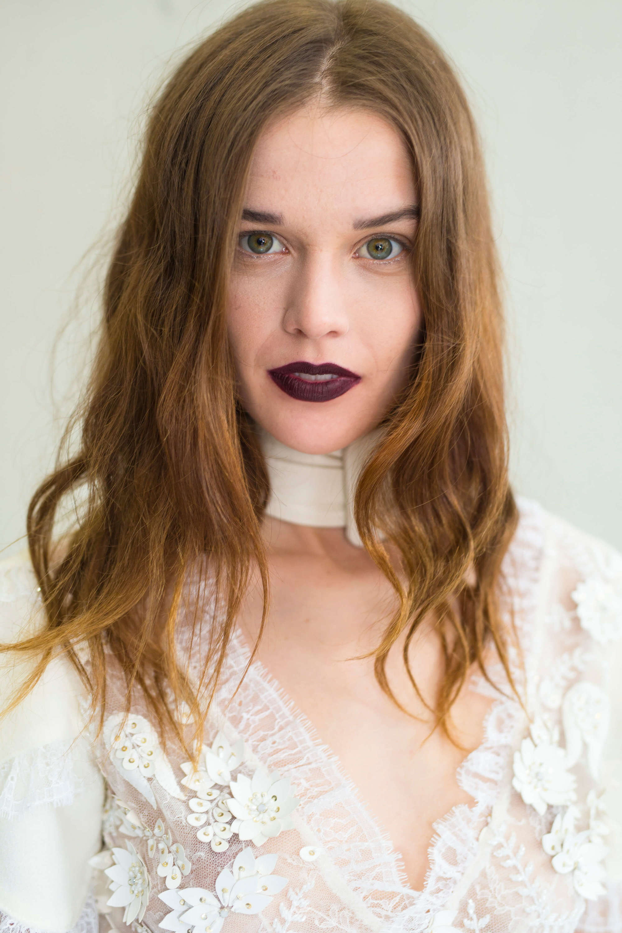 hairstyles for wavy hair: model with light golden brown medium length hair with soft waves through the ends wearing a white lace dress