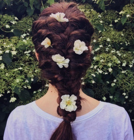 woman with red brown hair in a braid with flowers