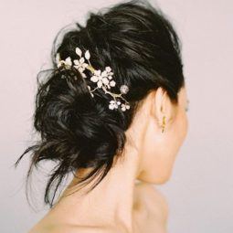 Wedding updos for long hair: Side shot of a woman long brown hair styled into a textured bun, complete with a barrette hair accessory.