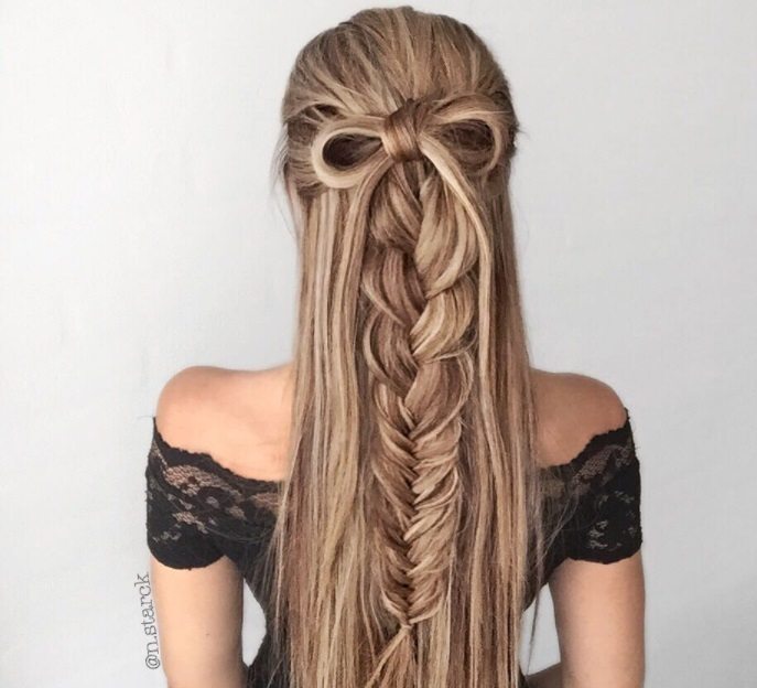 brunette woman with blonde highlights in a half-up, half-down bow hairstyle