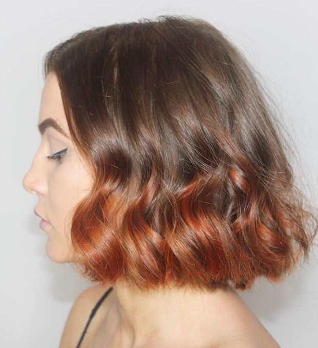 Short ombre hair: Woman with brown curly bob with copper ombre.